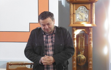 Przemawia dr Robert Zimny. W tle zabytkowy stojący zegar.