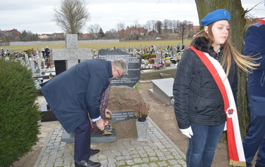 Wiceburmistrz składa znicz przy epitafium ks. Mateusza Zabłockiego. Obok warty harcerzy.