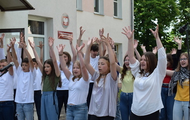 Ch&oacute;r podczas występu z rękami uniesionymi w g&oacute;rę.