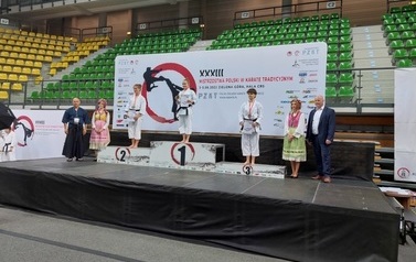 Trzy zawodniczki stoją na podium. Obok wręczający.