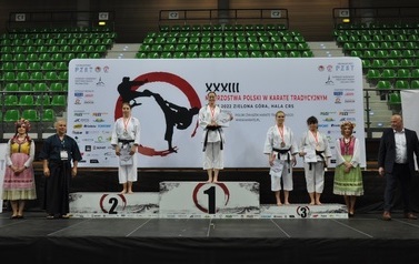 Cztery zawodniczki z medalami stoją na podium. Obok stoją wręczający.