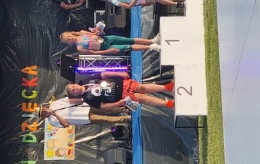 Tr&oacute;jka dzieci stoi na podium z medalami i nagrodami.