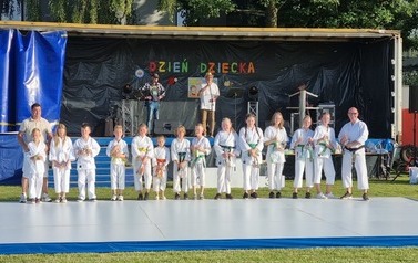 Dzieci w strojach karate pozują do zdjęcia.