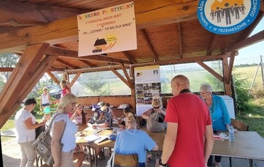 Uczestnicy konkursu plastycznego siedzą przy stołach i tworzą prace.