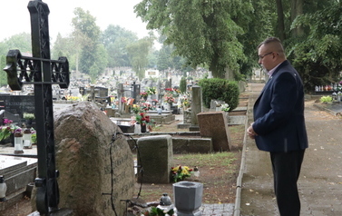 Burmistrz stoi przed obeliskiem w chwilę po złożeniu kwiat&oacute;w.