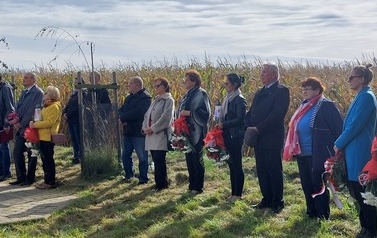 Delegacje z kwiatami stoją w jednym rzędzie.