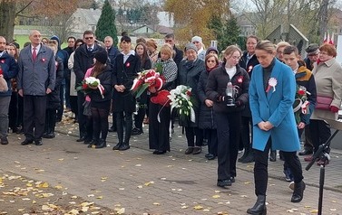 Na pierwszym planie delegacja SP nr 1 w drodze do zbiorowej mogiły. W tyle pozostali uczestnicy uroczystości.