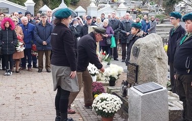 Na pierwszym planie delegacja ZHP składa kwiaty w miejscu pamięci narodowej. W tle pozostali uczestnicy uroczystości.