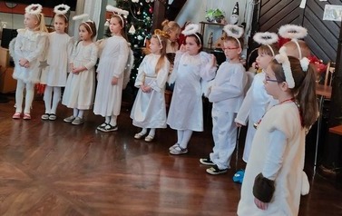 Dzieci przebrane za aniołki stoją w p&oacute;łokręgu.