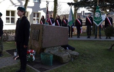 Na pierwszym planie obelisk, obok warty. W tle sztadary.