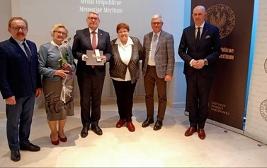 Członkowie komitetu z pracownikami IPN pozują do zdjęcia.