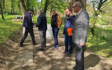 Pięciu mężczyzn stoi na oczyszczonej i wyr&oacute;wnanej części cmentarza. 