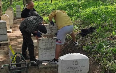 Trzech mężczyzn podczas prac umieszczania macew na cmentarzu.