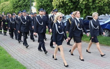Członkowie OSP w mundurach galowych maszerują przed bazyliką.