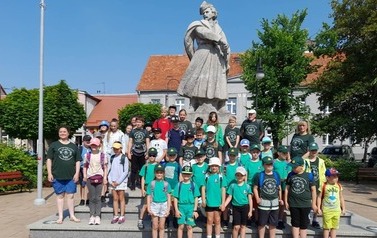 Grupa zuch&oacute;w i harcerzy pozuje do zdjęcia przy pomniku Jana Kilińskiego
