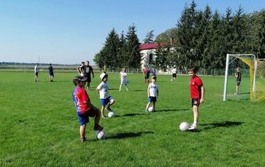Dzieci podczas gry w piłkę nożną na trawiastym boisku.