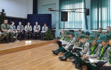 Widok na salę i siedzących ma krzesłach uczestnik&oacute;w spotkania. Wszyscy ubrani w mundury.