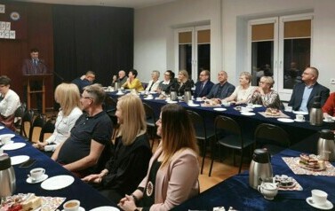 Widok na salę i siedzących przy zastawionych stołach społecznik&oacute;w.