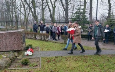 Do obelisku idzie delegacja uczni&oacute;w z wiązanką kwiat&oacute;w.