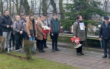 Na dziedzińcu stoją uczniowie oraz członkowie komitetu.