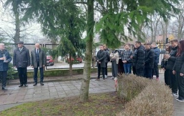 Na dziedzińcu stoją uczniowie oraz władze samorządowe.