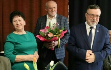 Od lewej stoją: prezes emeryt&oacute;w, przewodniczący rady trzymający bukiet kwiat&oacute;w oraz burmistrz.