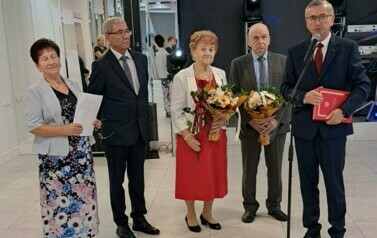 pięć os&oacute;b stoi, dwa bukiety kwiat&oacute;w