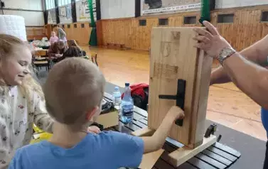 Hala sportowa. dwoje dzieci przy drewnianych małych drzewach.
