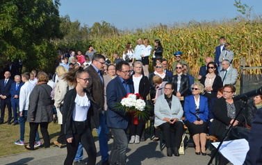 Delegacja ZSOiZ w Trzemesznie idzie złożyć wiązankę. W tle uczestnicy spotkania.