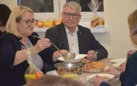 Wiceburmistrz i pani dyrektor nalewają zupę z wazy siedząc przy stoliku