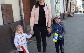 Dw&oacute;jka małych dzieci pozuje do zdjęcia trzymając w rączkach choragiewki.