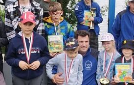 Przes stowarzyszenia pozuje w otoczeniu chłopc&oacute;w i dziewczynek trzymających nagrody.