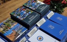 Na stole ułozone nagrody książkowe oraz teczki z listami - podziękowaniami.