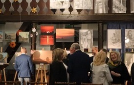 Na pierwszym planie uczestnicy spotkania. W tle prace.