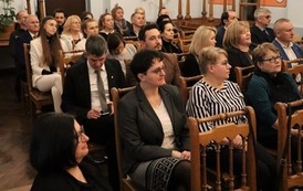 Widok na salę i siedzących na krzesłach uczestnik&oacute;w.