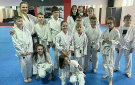 Grupa zawodnik&oacute;w w strojach karate pozuje do zdjęcia.