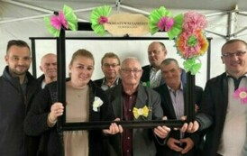 Grupa os&oacute;b pozuje do zdjęcia patrząc przez ozdobiona ramkę.