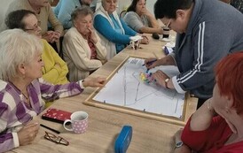 duża grupa os&oacute;b przy stole, kolorowe kartki 