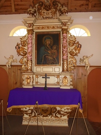Ołtarz z obrazem Matki Boskiej oraz złotymi zdobieniami.
